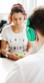 Två studenter med hörlurar och mobiltelefoner
