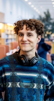 En ung student med hörlurar på ett bibliotek