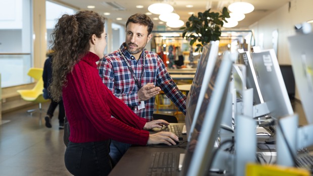 En bibliotekarie och en låntagare i samtal vid en lånedisk.