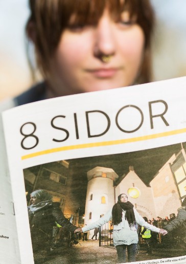 Ett foto av en ung kvinna som läser 8 Sidor. Bilden är länkad till en artikel om tidningen på 8sidor.se