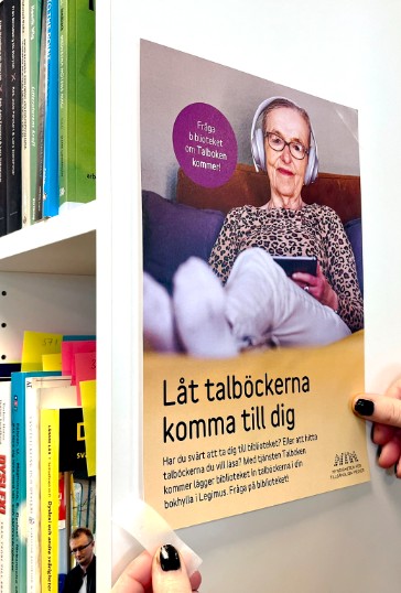 En person sätter upp en affisch om Talboken kommer. 